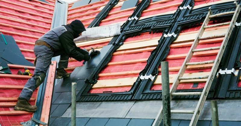 a roofer replacing the tiles on a house roof.